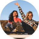 Two girls sitting on a top of a car